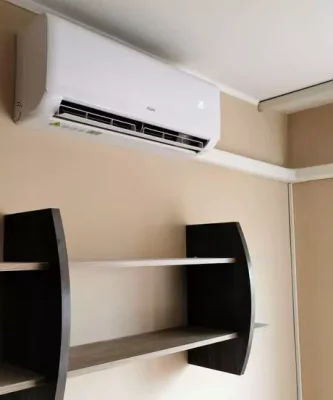 وحدة تكييف سبليت جديدة من ماركة AUX مثبتة بشكل أنيق على الحائط فوق رف.